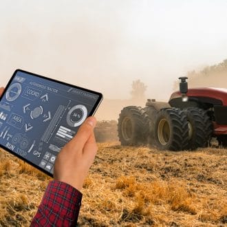 A farmer with digital tablet controls an autonomous tractor