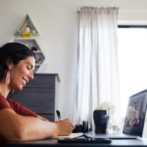 Lady making a list in front of laptop.