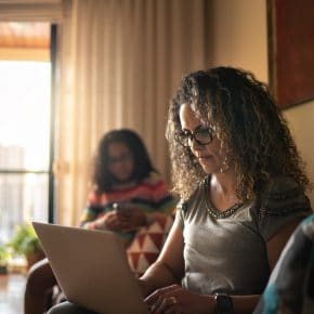 Mother and daughter at home on mobile devices.