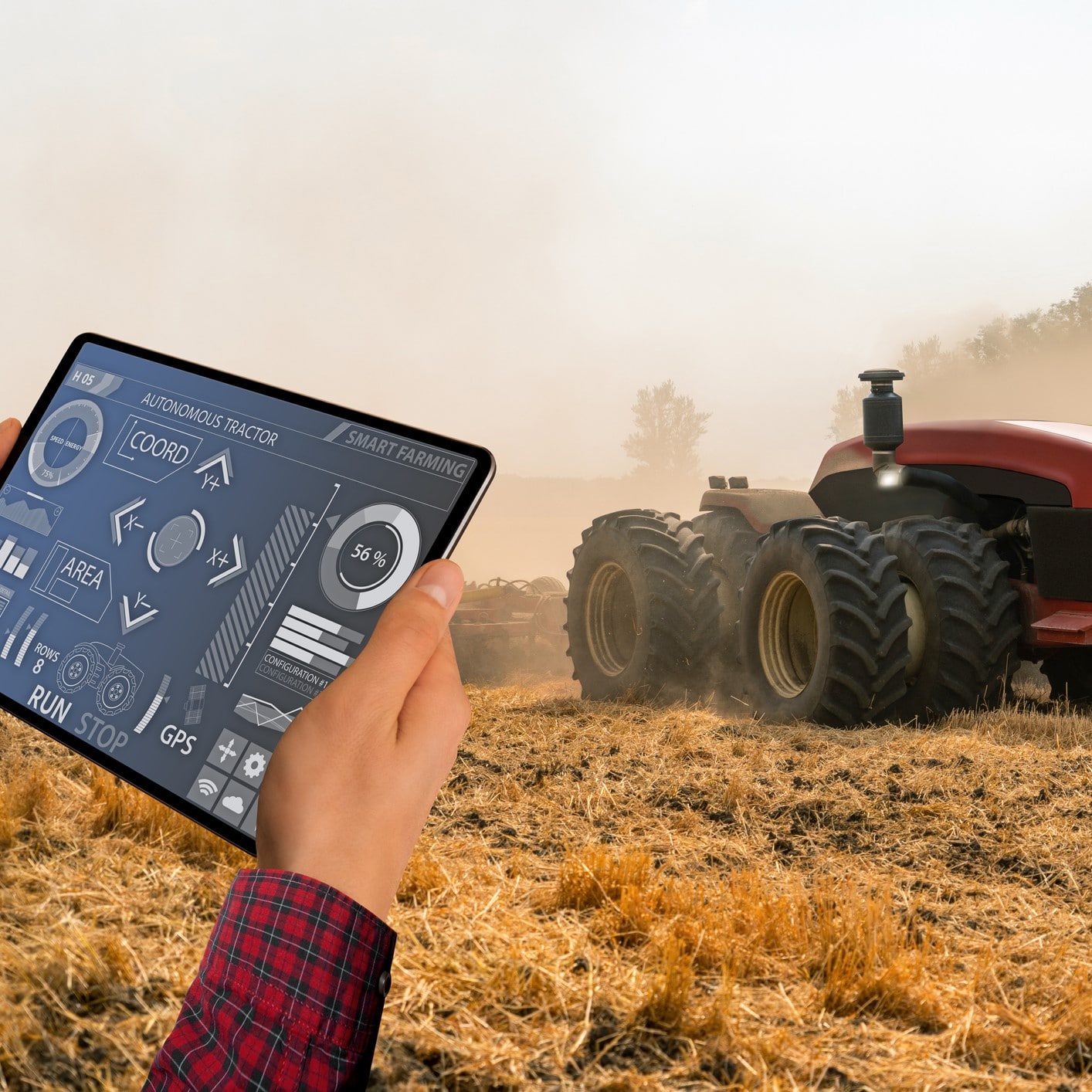 A farmer with digital tablet controls an autonomous tractor