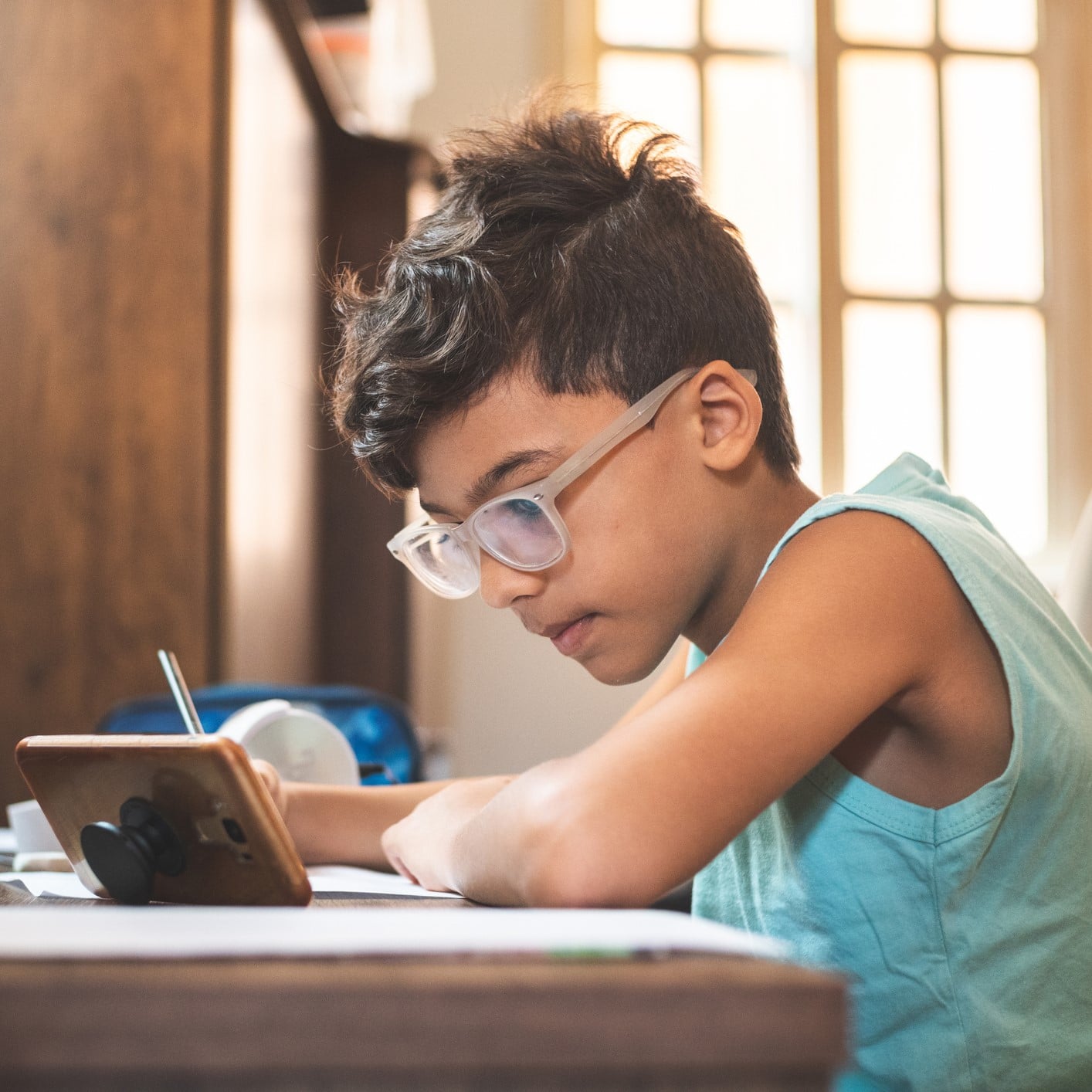 Kid on phone doing schoolwork